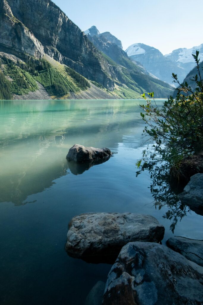 Peaceful scene of Lake Louise with towering Rockies reflecting in its clear turquoise water.